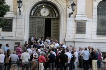 Customers wait outside a bank in Athens, Greece