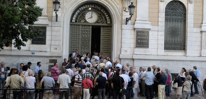 Customers wait outside a bank in Athens, Greece