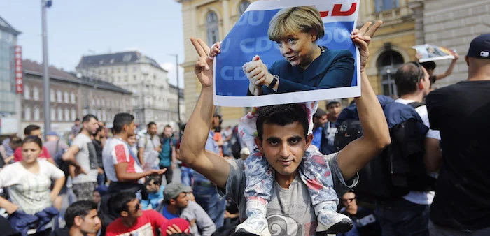 Man holds poster of German Chancellor Angela Merkel during march of refugees fleeing Hungary