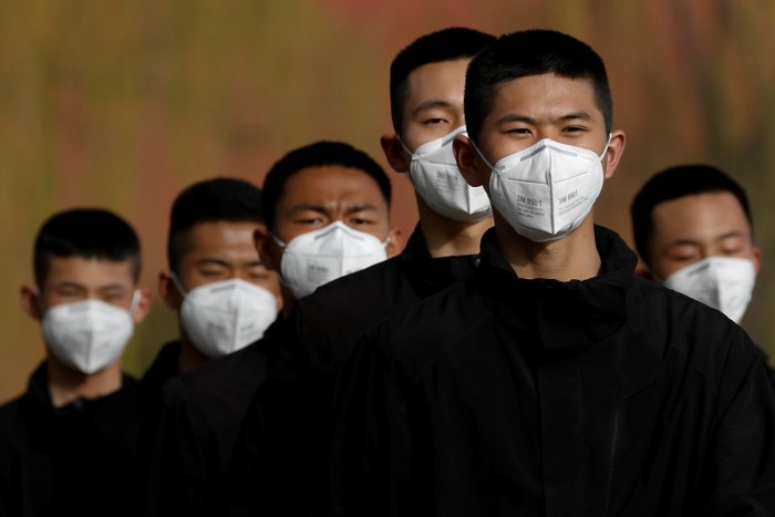 Security personnel wearing face masks to contain the spread of coronavirus disease (COVID-19) walk along a street outside Forbidden City in Beijing, China March 18, 2020. REUTERS/Carlos Garcia Rawlins TPX IMAGES OF THE DAY - RC2CMF9VZ6A9