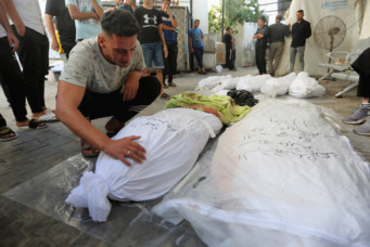 A Palestinian man reacts next to the bodies of Palestinians killed in Israeli strikes