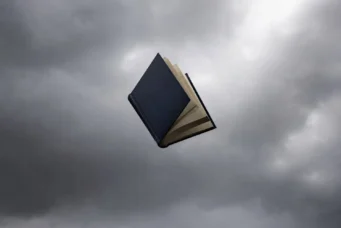 A book opens in free fall with a stormy sky in the background.