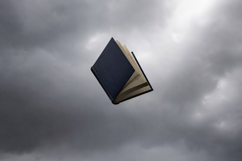 A book opens in free fall with a stormy sky in the background.