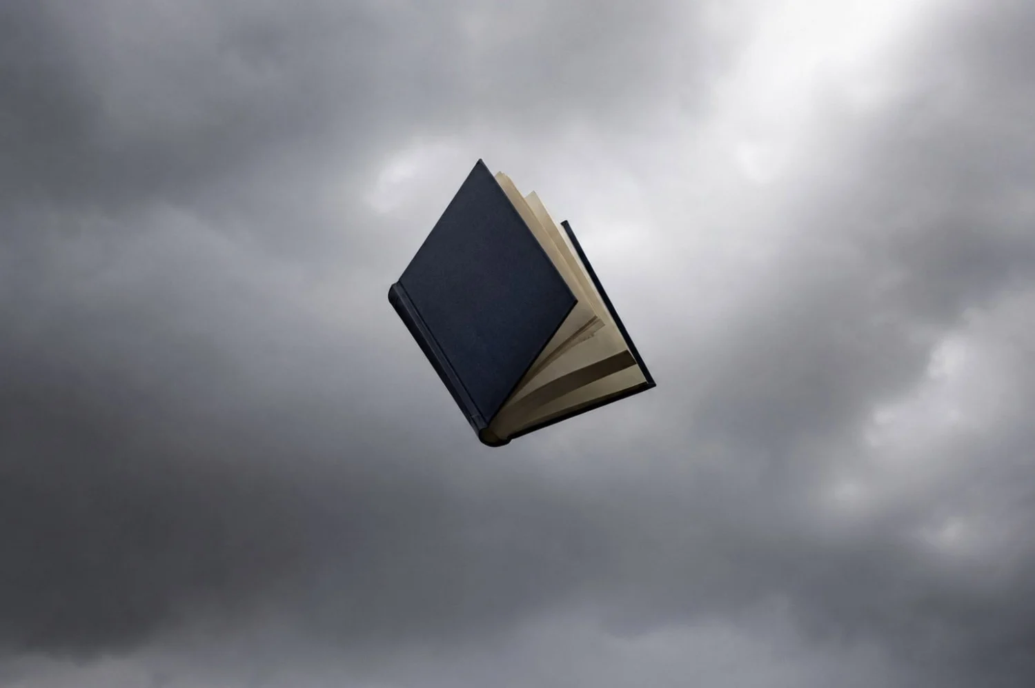 A book opens in free fall with a stormy sky in the background.